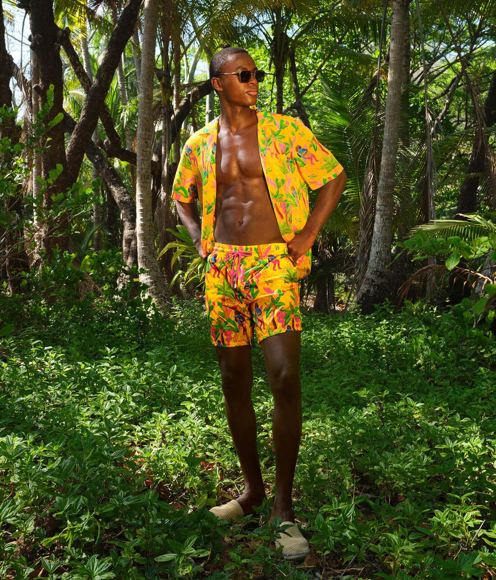 A man in the jungle wearing matching shirt and swim shorts.